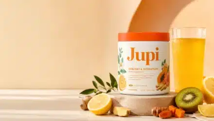 Jupi Hydration review showing the citrus ginger supplement tub with a yellow hydration drink, lemon, ginger, turmeric, kiwi, and papaya