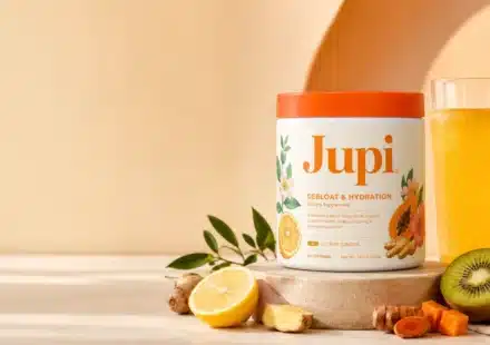 Jupi Hydration review showing the citrus ginger supplement tub with a yellow hydration drink, lemon, ginger, turmeric, kiwi, and papaya
