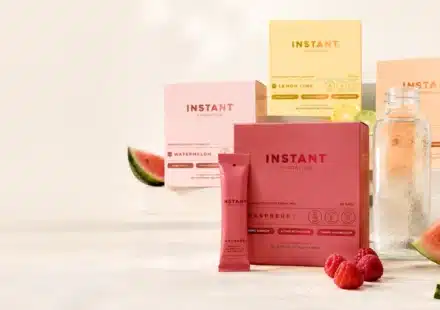 Instant Hydration packets and electrolyte drink mix boxes in multiple flavors beside a clear water bottle